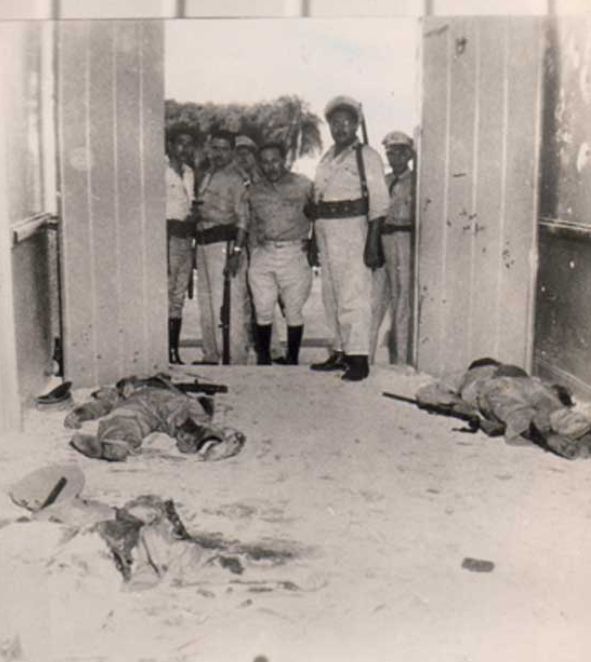 Un grupo de soldados contempla los cadáveres de tres combatientes a la entrada de una oficina del Moncada. 